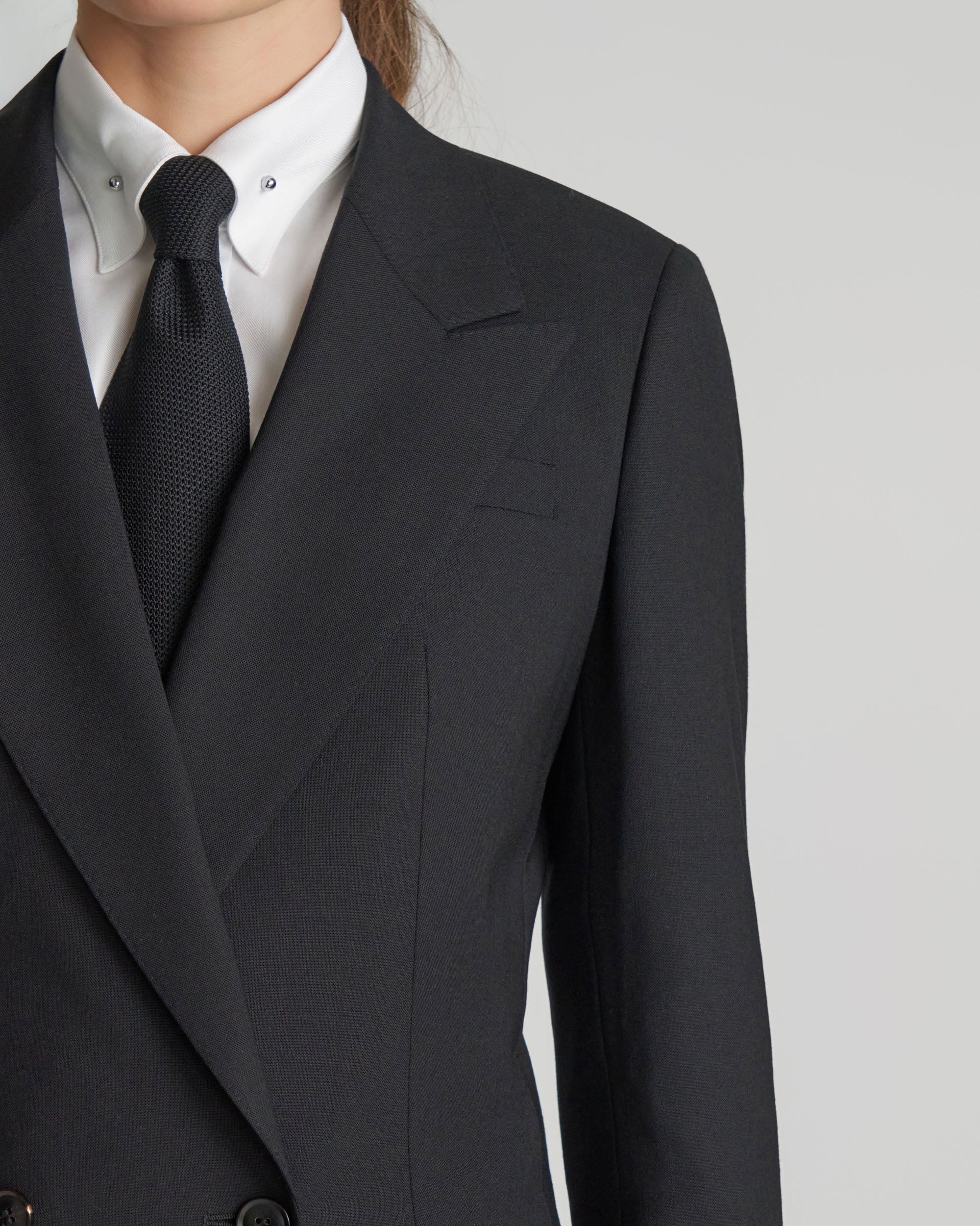 Black suit jacket with white shirt and dark tie on a light gray background