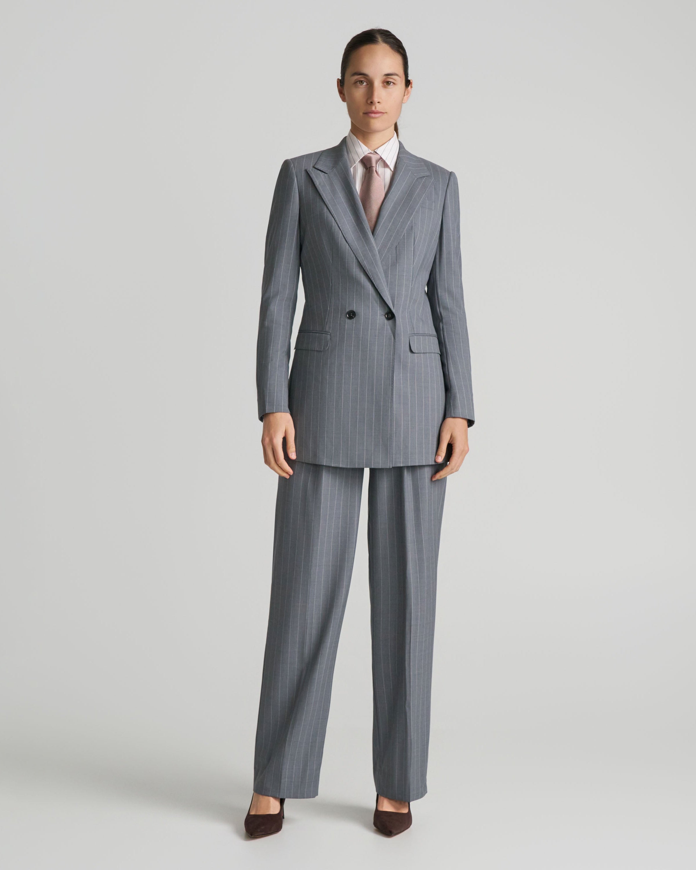 Woman wearing a gray pinstripe suit on a light gray background