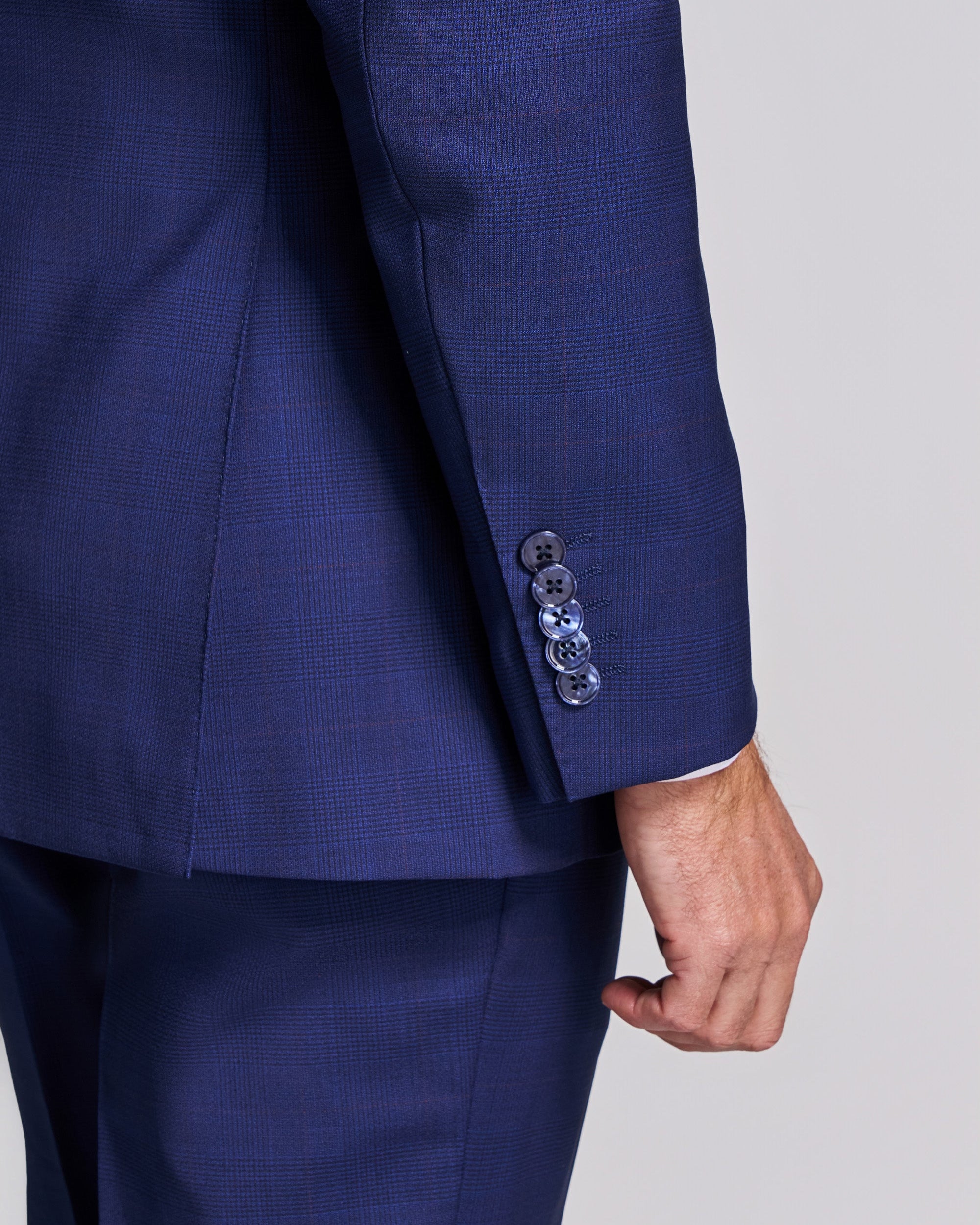 Close-up of a blue suit jacket with a hand visible on a light gray background