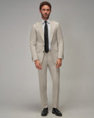 Man wearing a beige suit with a black tie on a gray background