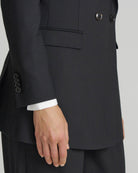 Black suit jacket with white shirt cuff on a neutral background